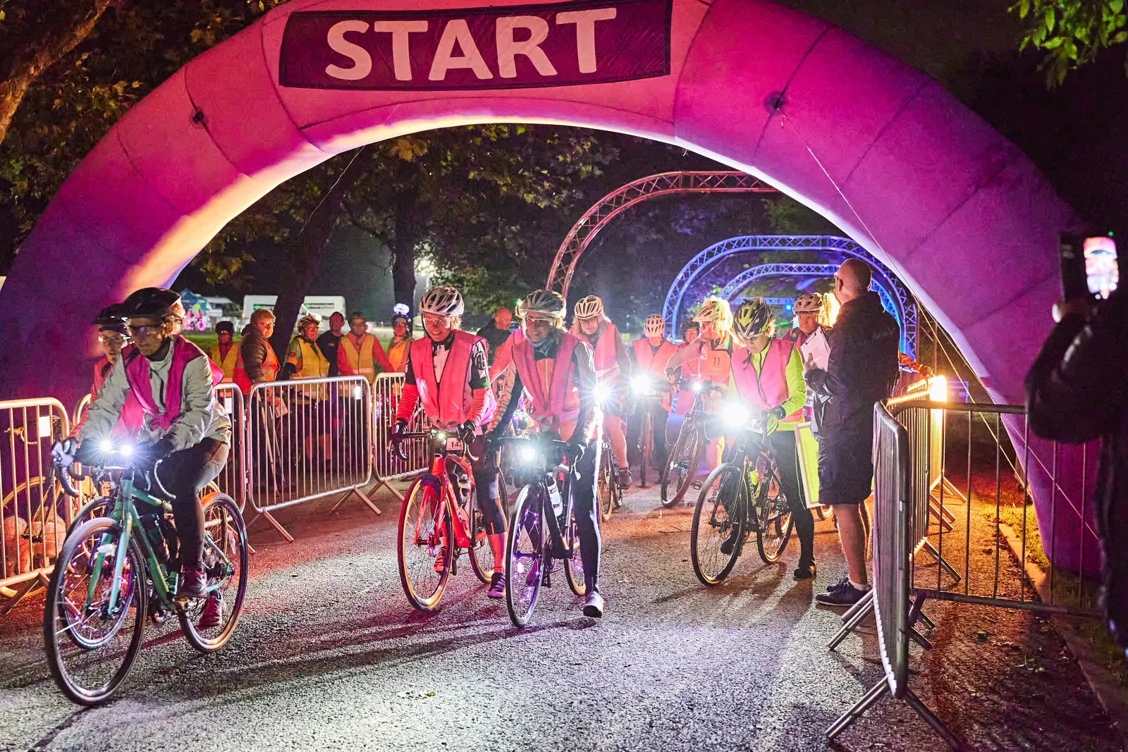 Riders stream under the start arch at the overnight charity ride in Heaton Park